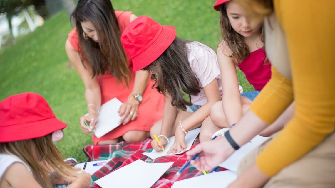 Children and nanny enjoying an outdoor drawing session in a sunny park.