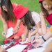Children and nanny enjoying an outdoor drawing session in a sunny park.
